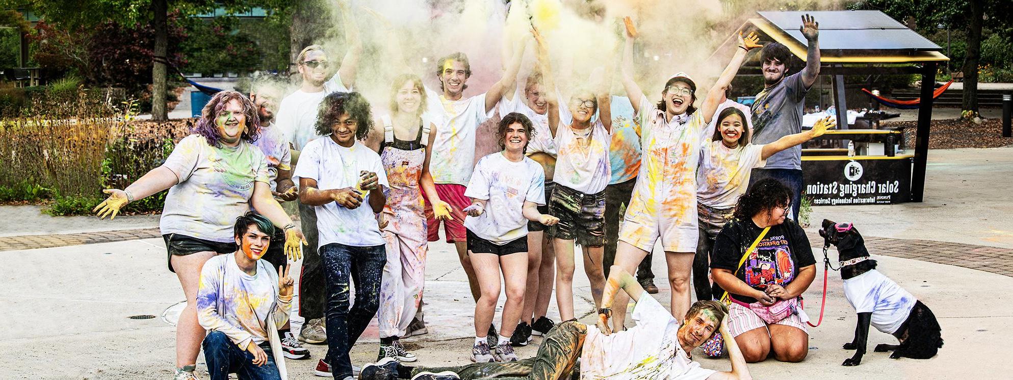 Students throw colorful chalk in the air after a color run on campus.